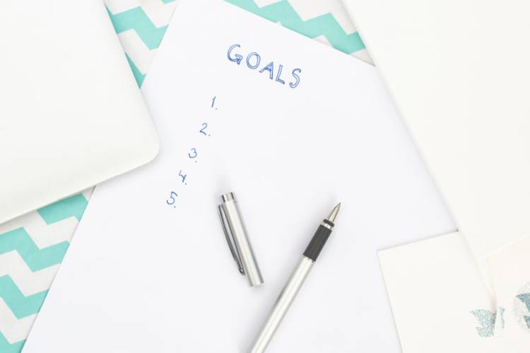 writing down a list of goals on a piece of paper.